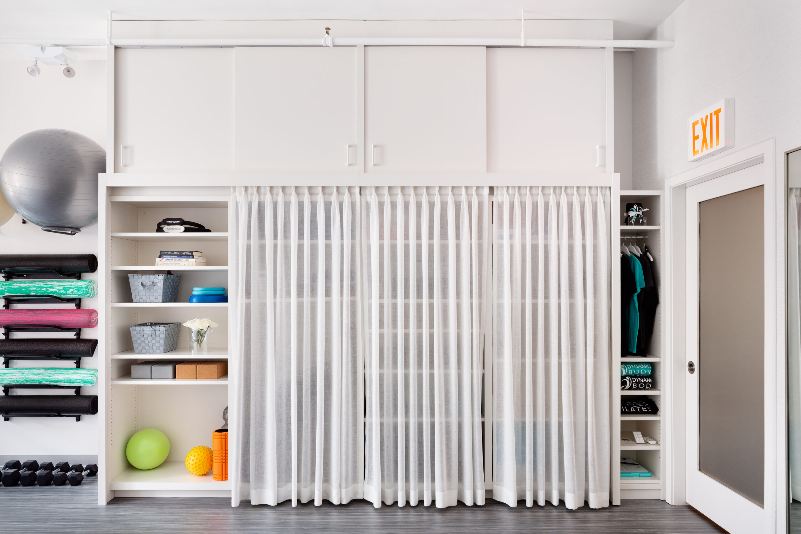 Tall built-in shelving unit with cubbies for storage next to a translucent sliding door to the waiting area at the Pilates studio